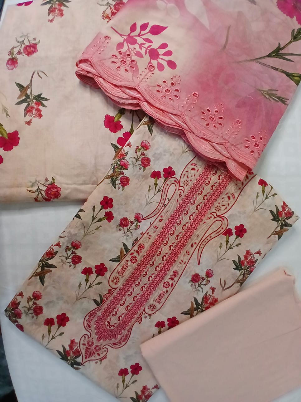 Detailed close-up of heavy floral embroidery and lace-style cutwork design on premium pink lawn shirt fabric